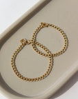 14k gold fill Demi Alexandra Bracelet in adult and children's sizes laid on a gray plate in the sunlight