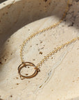 14k gold fill Eternity Necklace placed on a cream colored dish. This necklace and plate is sitting in the sunlight. This necklace features an open circle disc that is attached to our simple chain. Token Jewelry is hypoallergenic and nickel free. - Token Jewelry