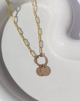 A textured chain-link style 14k gold fill necklace chain featuring a gold hoop, from which hangs two stamped discs