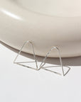 sterling silver Sunday Earrings laid on a gray plate in the sunlight. These earrings feature a triangle look easy to thread in your ear.