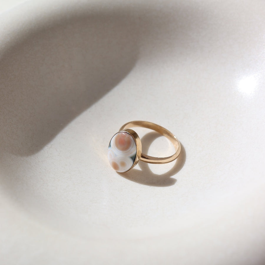 a 14k gold fill hand-set ocean jasper ring laid out on a cream colored backdrop in the sun