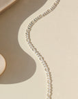 925 sterling silver Gio chain laid on a tan paper in the sunlight.