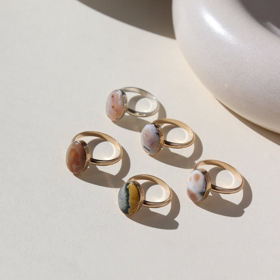14k gold fill and sterling silver hand-set ocean jasper rings laid out on a cream colored backdrop in the sun