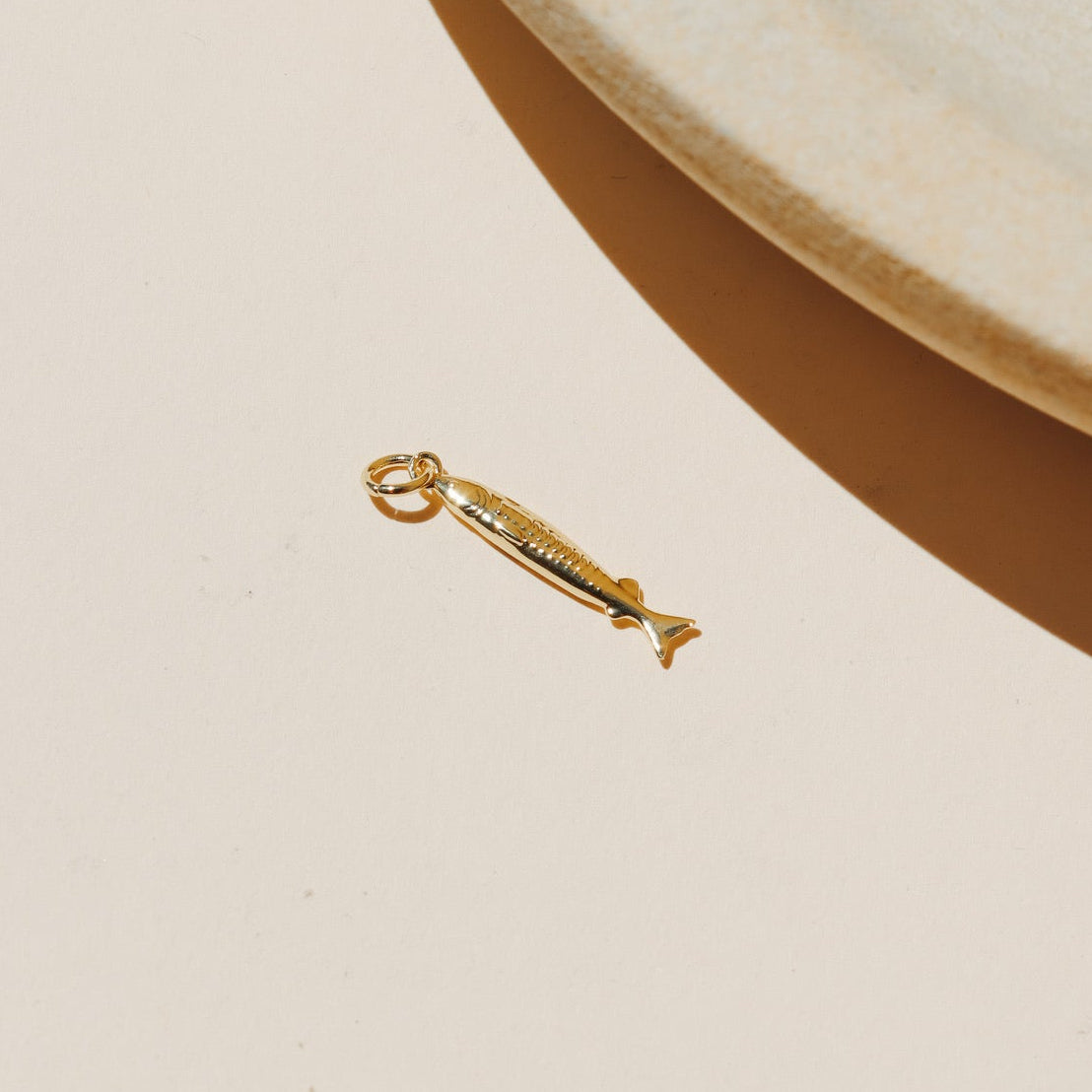 Small gold sardine fish charm with detailed texture and polished finish.