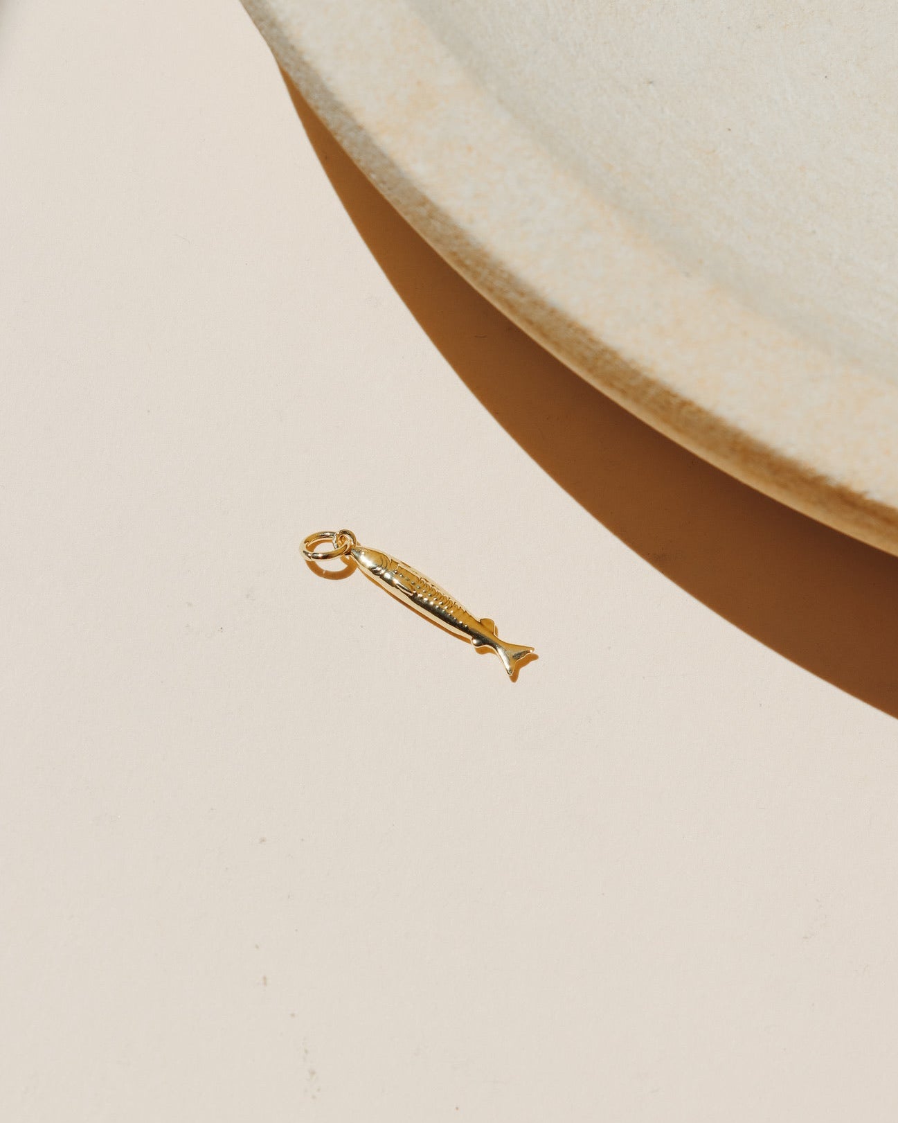 Small gold sardine fish charm with detailed texture and polished finish.