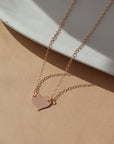 14k Rose gold fill heart necklace on a 14k gold fill chain, photographed on a ceramic dish