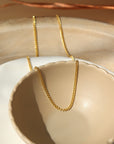 14k gold fill La Mer Chain set in a tan jewelry plate in the sunlight. - Token Jewelry