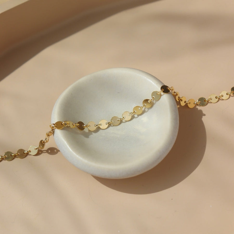 14k gold fill Starlight Bracelet laid on a white plate in the sunlight.This bracelet features a circle like chain linked together.  - Token Jewelry