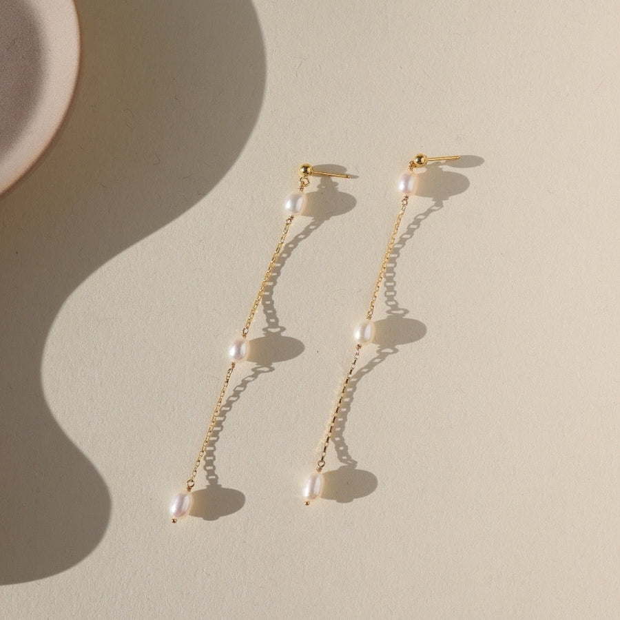 14k gold fill Floating Pearl Earrings. Wedding Jewelry. Classic and Modern. Sterling Silver or 14k Gold Fill. Token Jewelry, handmade, hypoallergenic and waterproof. These earrings are a stud earring with three pearls spaced out 1/2 an inch from one another.