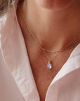 Celine Necklace featuring smooth teardrop moonstone gemstone with blue flash hanging from a dainty 14k gold filled cable chain with spring hook clasp. Fashion Jewelry handmade in by Token Jewelry in Eau Claire, WI  Edit alt text