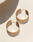 14k gold fill Florence hoops laid on a white plate in the sunlight