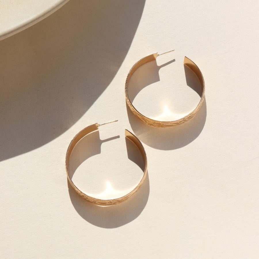 14k gold fill Florence hoops laid on a white plate in the sunlight