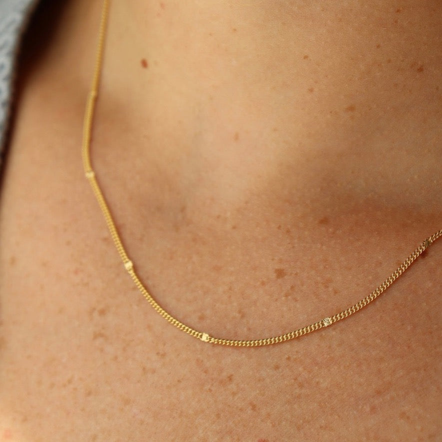 Model Wearing 14k Sunny chain. This necklace features a simple chain with an extra sparkle every 1/2".