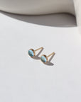4mm Blue Topaz gemstones set in a 14k gold fill bezel stud earring and placed on a white plate for display. Sold as a pair and perfect for single or double pierced ears.