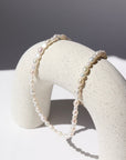 14k gold fill endless pearl necklace laid on a white plate.