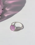 925 Sterling Silver Pippa Ring laid on a white paper in the sunlight. This ring features a sprial band with a pink kunzite gemstone.  