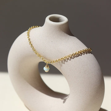 14k gold fill Peruvian Opal Bracelet laid on a tan jewelry display in the sunlight.