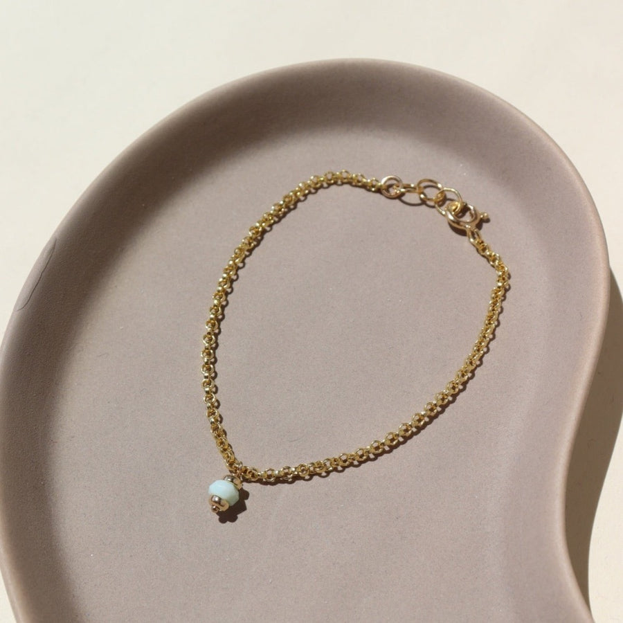 14k gold fill Peruvian Opal Bracelet laid on a tan jewelry display in the sunlight.