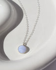 925 sterling silver Blue Lace Agate Necklace placed on a white plate in the sunlight. This Necklace features our simple chain along with a Blue Lace Agate gemstone.