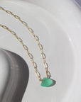 14k gold fill Sea Green Necklace placed on a white plate in the sunlight. This Necklace feature our Cosette Chain which is a paperclip chain. This chain is then connected with a green chalcedony gemstone.