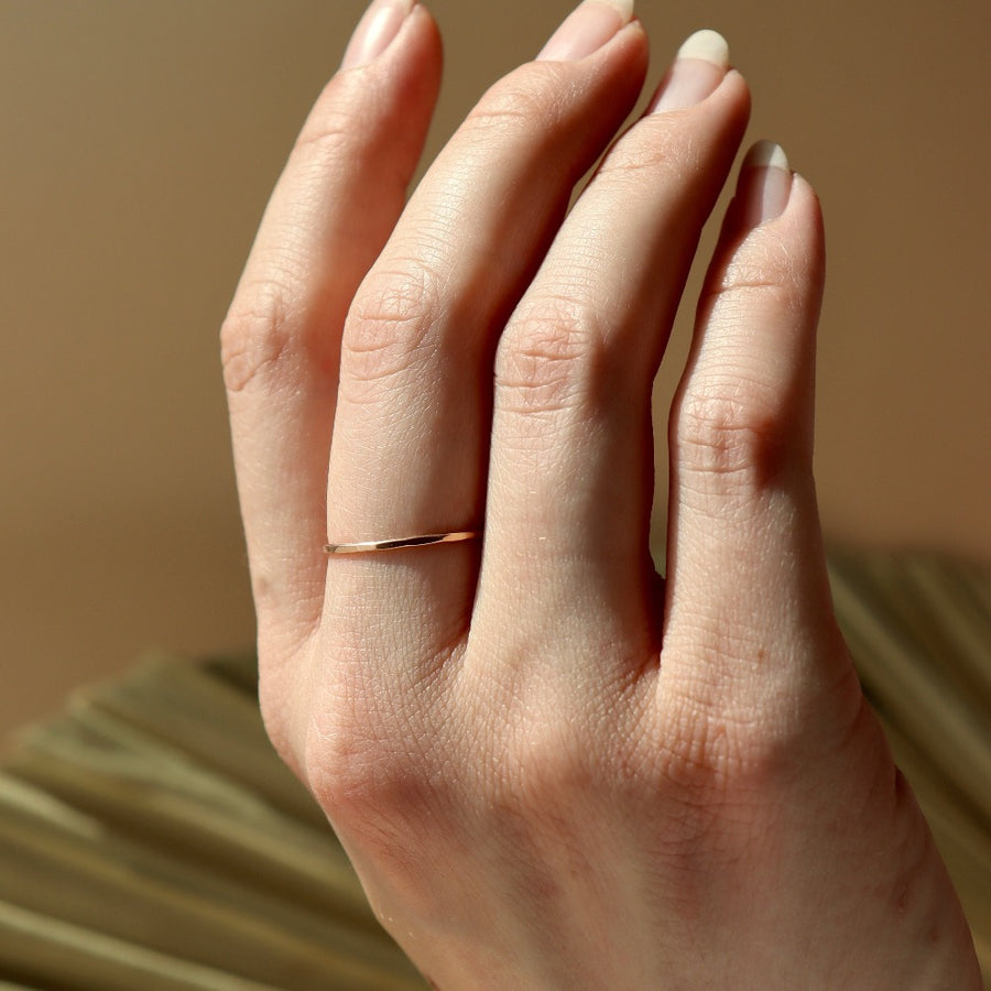 dainty hammered gold stacking ring on model handcrafted by Token Jewelry in Eau Claire, Wisconsin. This ring features a simple band with hammering on the outside. 