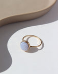 14k gold fill Blue Lace Agate Ring laid white paper in the sunlight. This Ring Features a simple band with light hammering around the sides, this ring also features the Blue Lace Agate Ring.