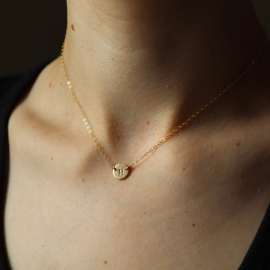 Model wearing a 16" 14k gold fill Anchored Initial Necklace with the initial "H" stamped on the coin pendent.