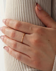 Model is wearing the Essential stacking ring on hear middle finger grabbing her upper arm. These rings are lightly hammered gold stacking ring, handmade by Token Jewelry in Eau Claire, Wisconsin