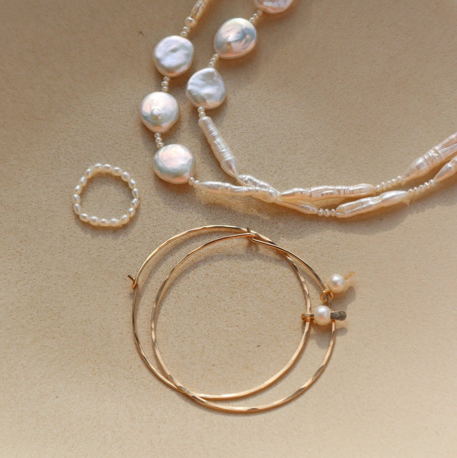 Margot ring laid on a plate paired with a Pair of Emma hoops and the Evelyn pearl necklace