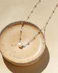 925 sterling silver beaded chain with a pretty single pearl necklace laid on a white plate in the sunlight. 