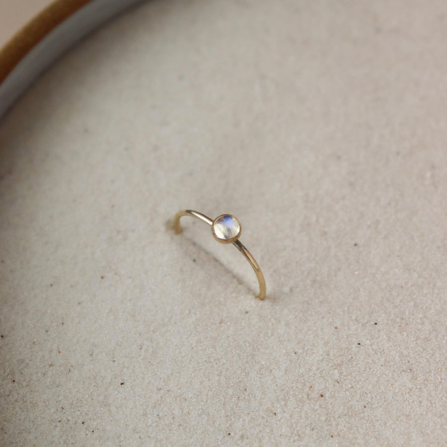 14k gold fill moonstone ring 4mm set in the sand. This ring features a simple band with a moonstone gemstone bezeled to it.