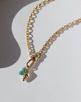 14k gold fill anklet with a swivel push-gate clasp holding a seashell charm and a turquoise charm, photographed on a sunny table