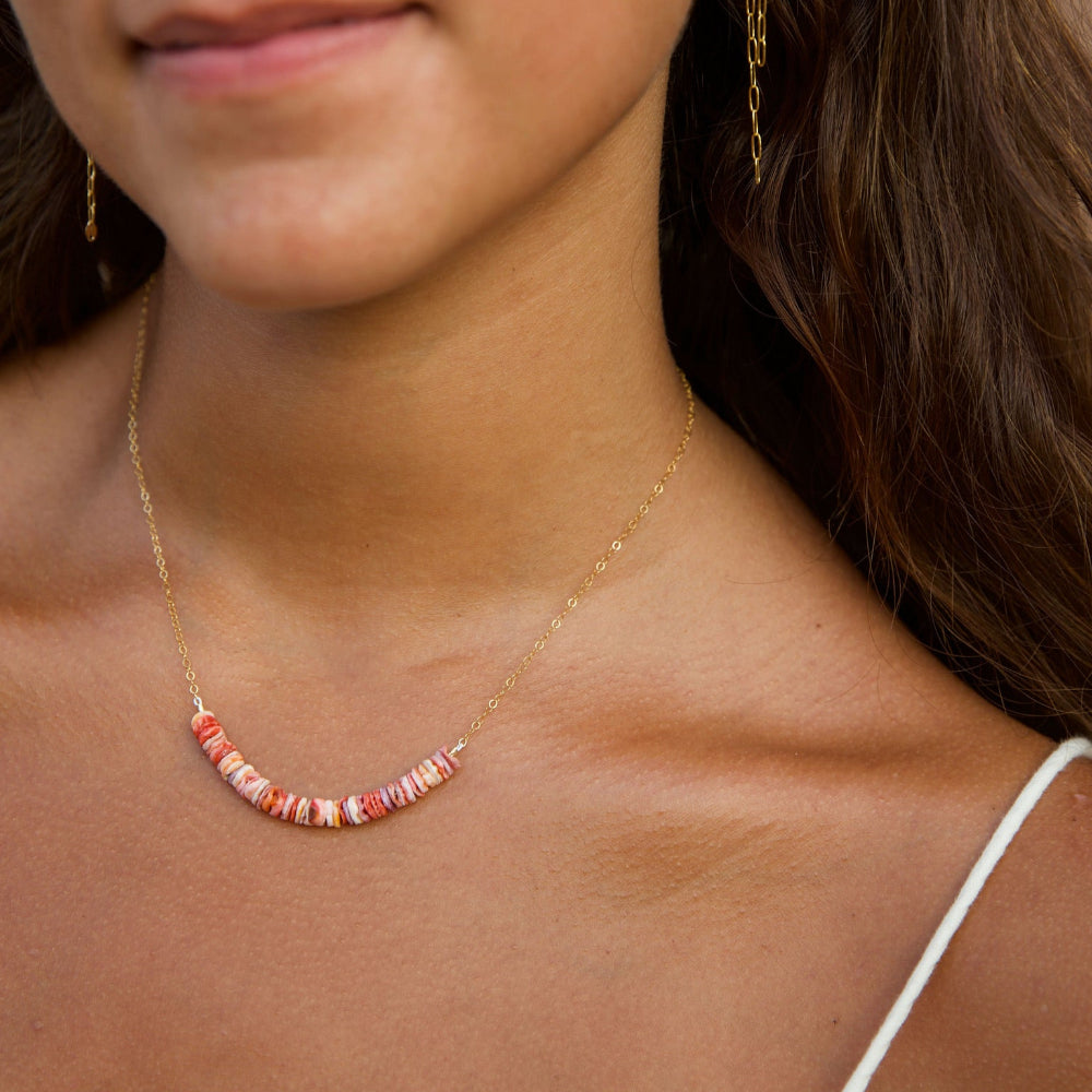Close-up of a woman wearing a delicate necklace with beads.