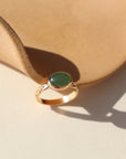 A 14k gold fill entwined band with a 8x10 jade gemstone in a gold bezel. The ring is displayed on a orange dish. 