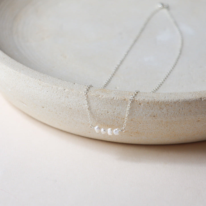 sterling silver delicate chain necklace with 3 fresh water pearls on a light dish