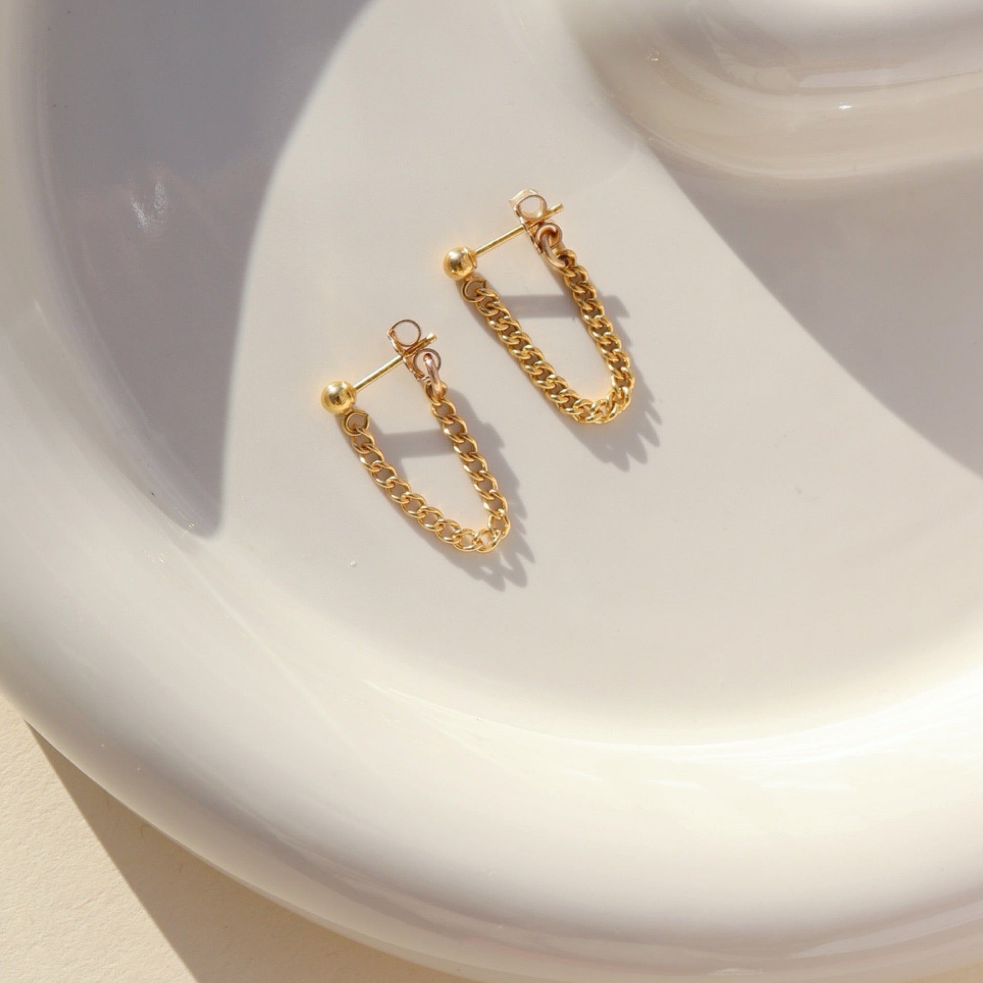 14k gold fill small curb chain stud earrings on a light dish