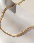 La Mer Necklace in 14k gold fill on a white plate in the sunlight.