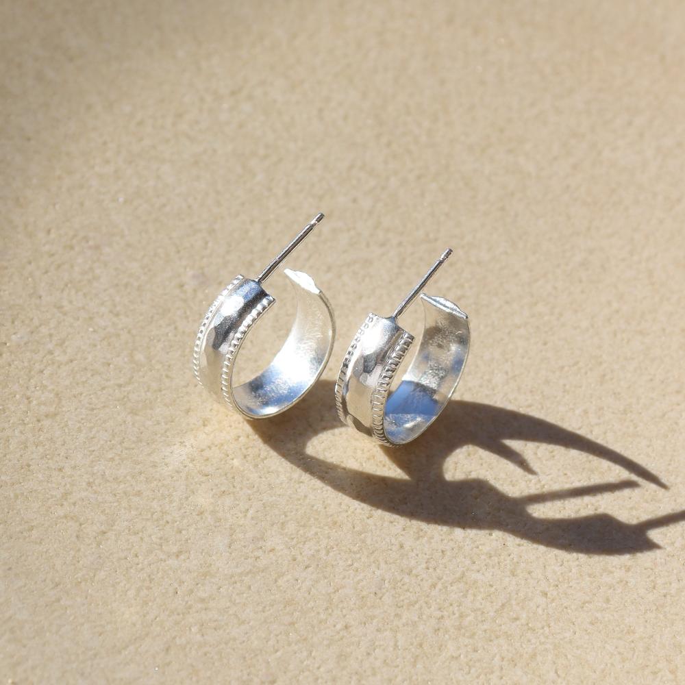 sterling silver hammered textured stud hoop earrings on a light background