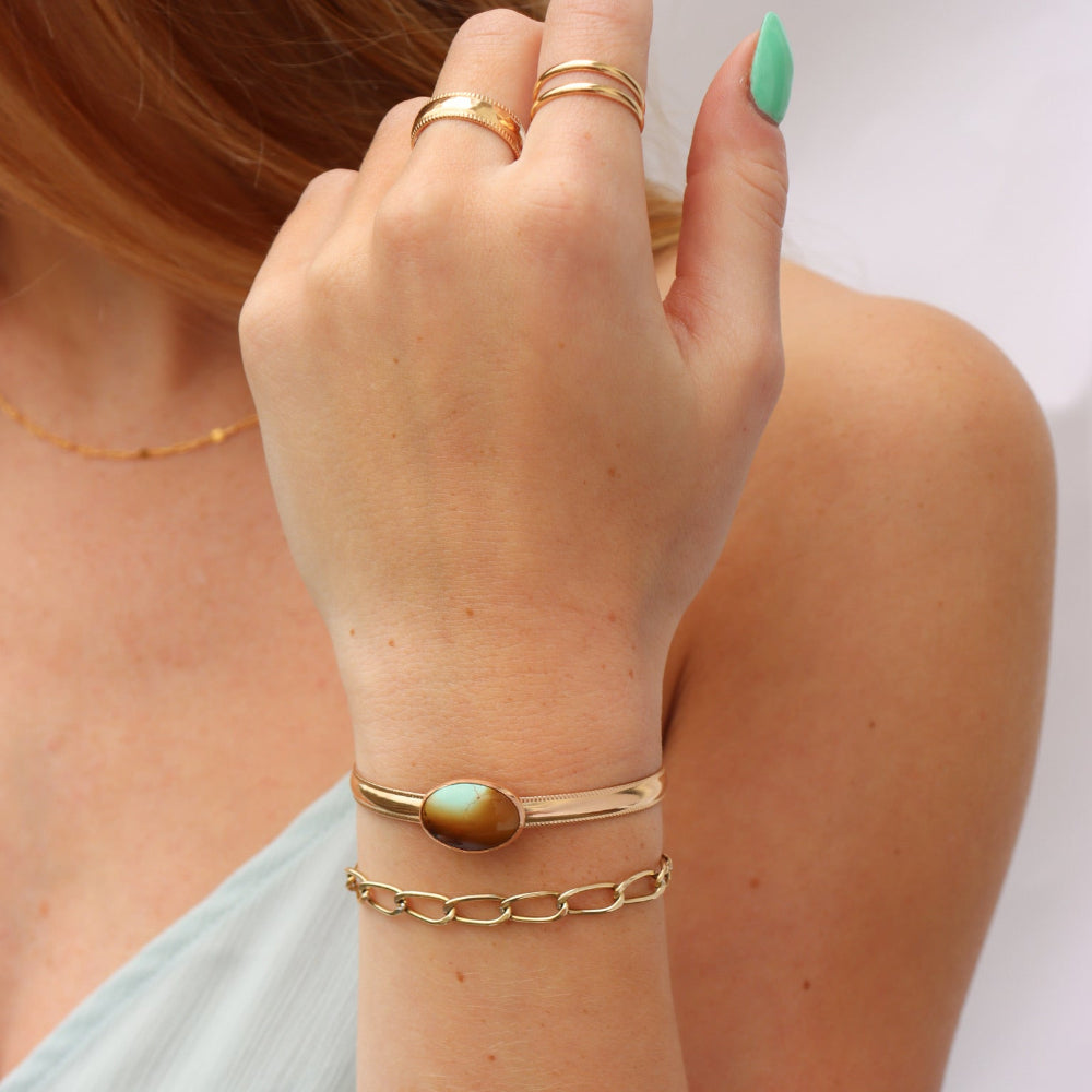 Model wearing a 14k gold fill smooth cuff with a 13x18mm turquoise stone set at its center