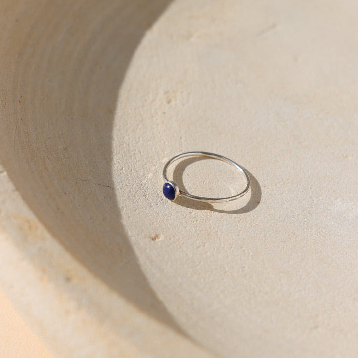 sterling silver bezel ring with 4mm lapis lazuli gemstone on a light dish
