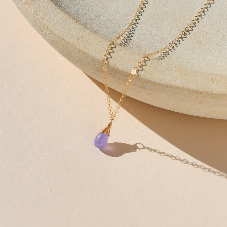 delicate 14k gold fill chain necklace with teardrop hackmanite pendant on a light dish