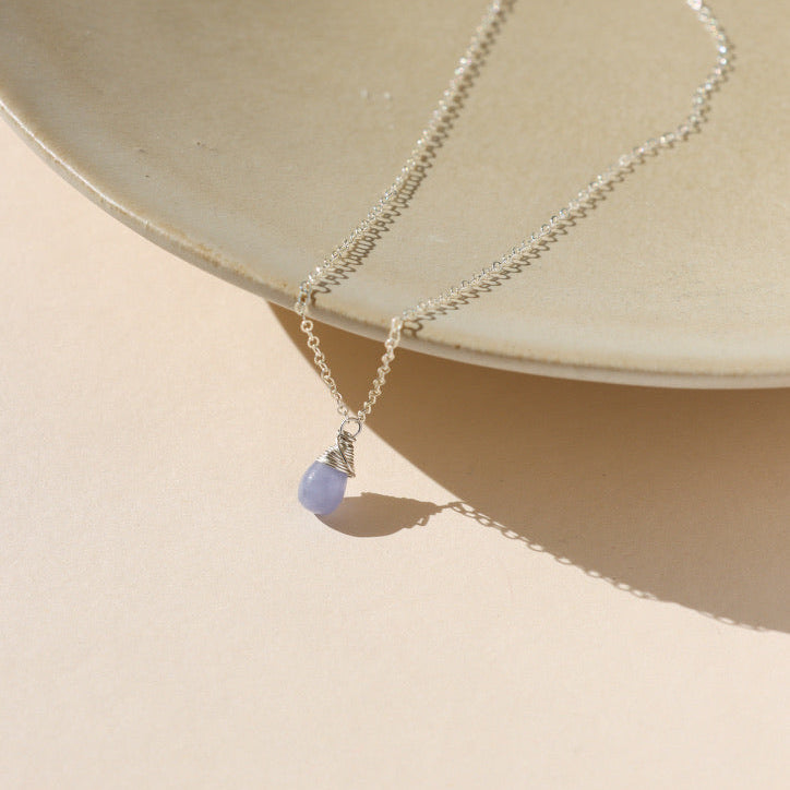 delicate sterling silver chain necklace with teardrop hackmanite pendant on a light dish