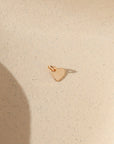 14k gold fill heart charm with jump ring on a light background in the sunlight