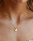 Model wearing a 14k gold fill simple chain with a stamped disc with a small bunny, paired with a small opal wire wrapped gemstone. 