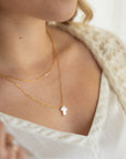 model wearing 14k gold fill paperclip chain necklace with a mother of pearl cross pendant 