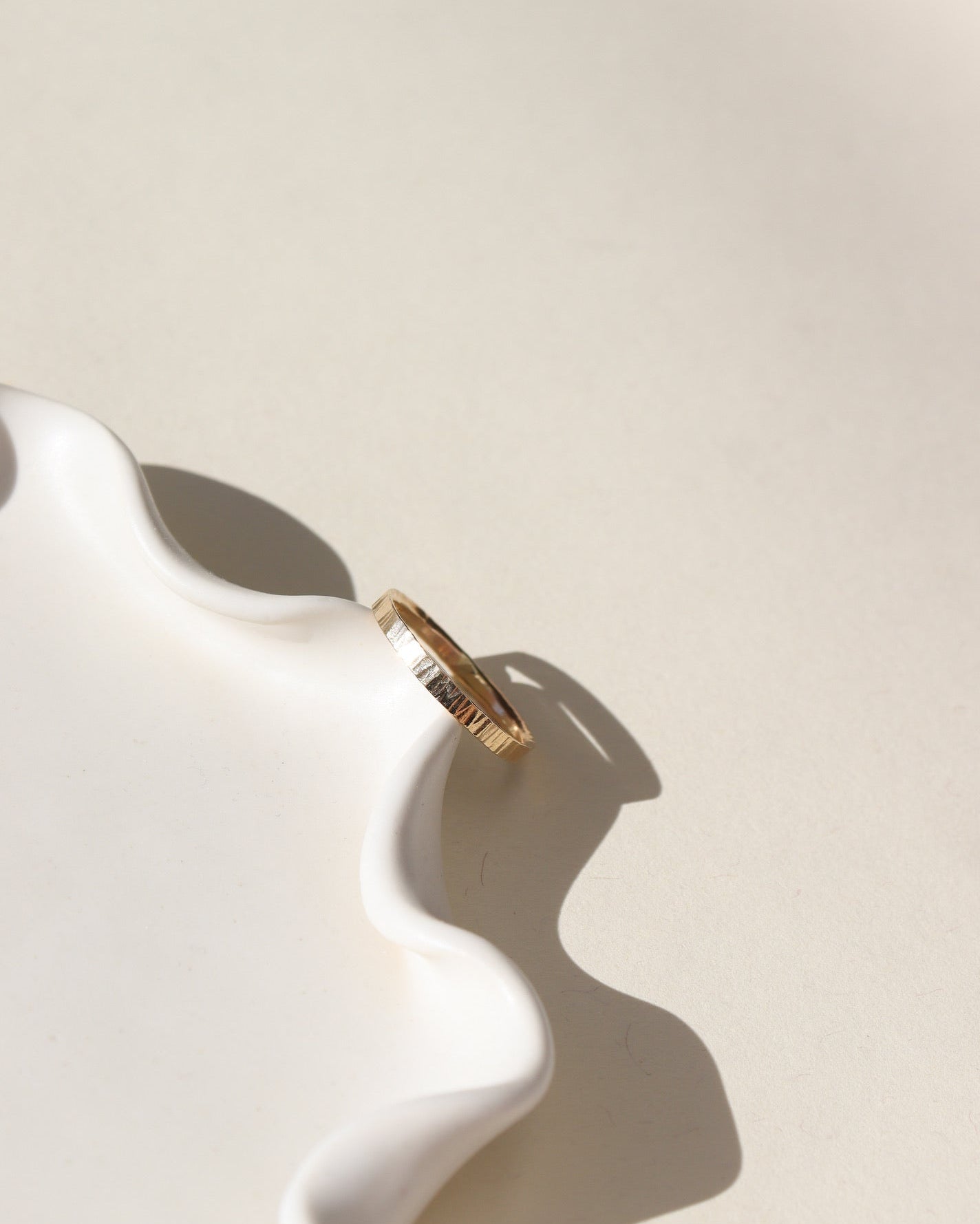 lightly textured 14k solid gold ring on a wavy dish in the sunlight