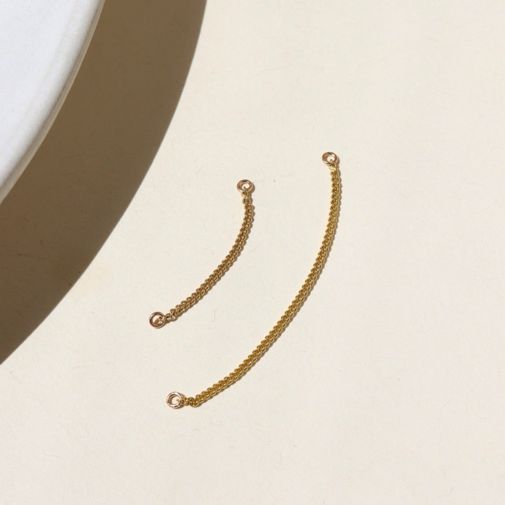 14k gold fill, curb chain offered in small and large with a 1.6 jump ring at each end of the chain. The connectors are displayed on a cream backdrop in the sunlight 