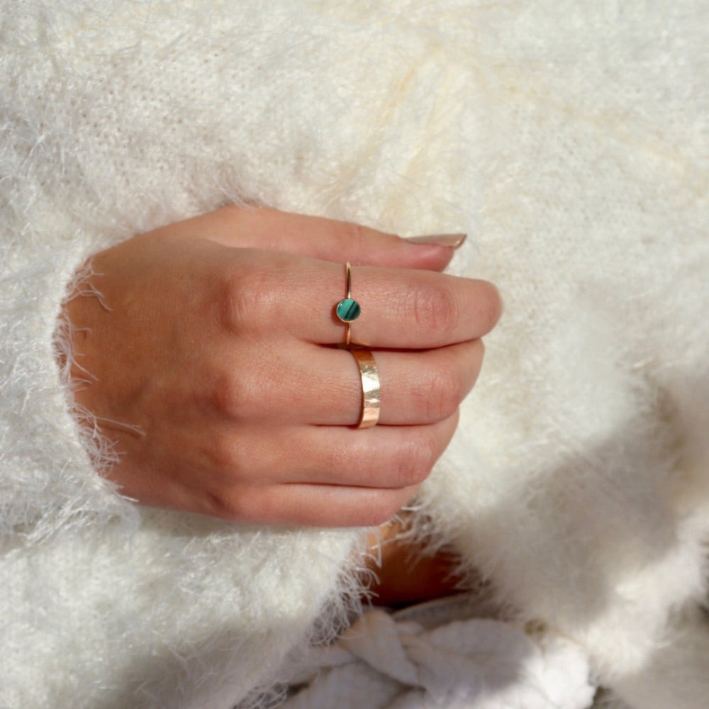 Model wearing a 14k gold fill skinny band featuring a 5mm malachite stone set in a gold bezel. The model is wearing a whitr fuzzy top. 