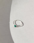 A sterling silver skinny band featuring a 5mm malachite stone set in a silver bezel. The 5mm Malachite Ring is displayed on a cream dish. 