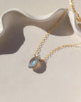 14k gold filled Marquise Necklace laying on a white ceramic dish.